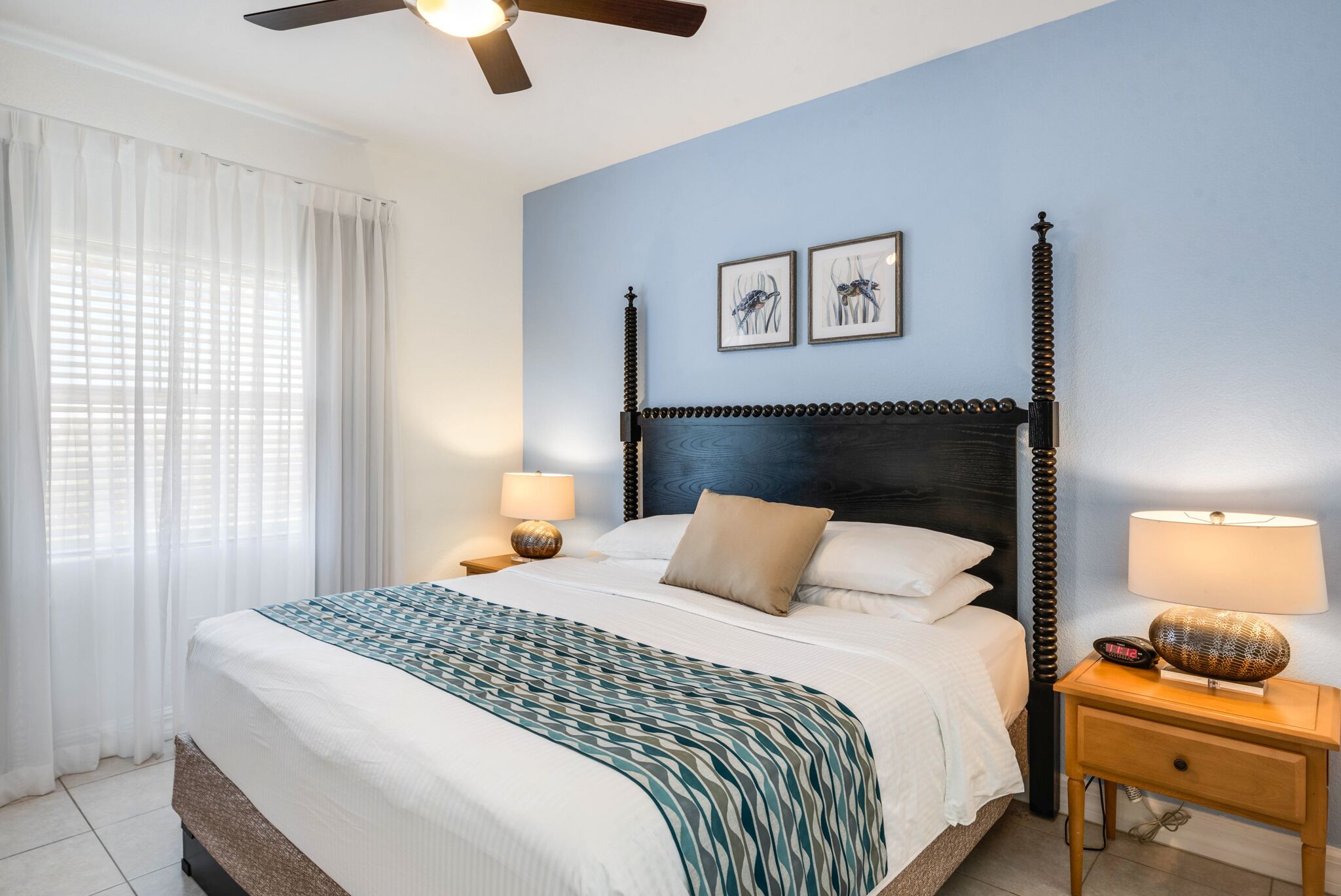 A bedroom with a bed, a nightstand, a lamp, and a ceiling fan.