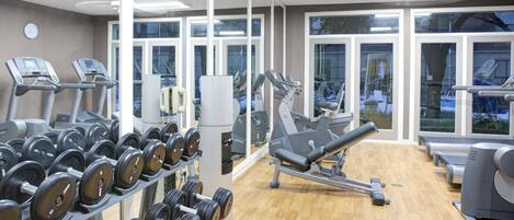 A gym with treadmills, elliptical machines, and a rack of dumbbells.