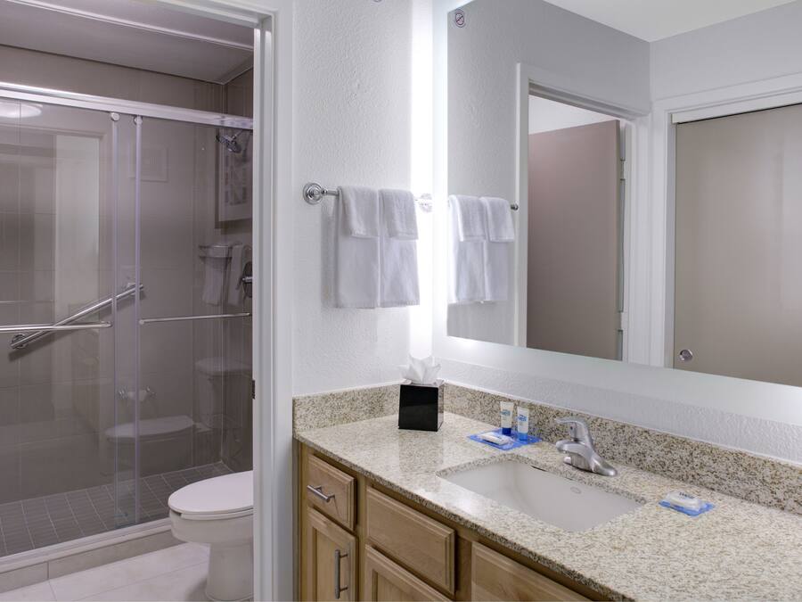 A modern bathroom with a glass-enclosed shower, a toilet, a sink with a mirror, and wooden cabinets.