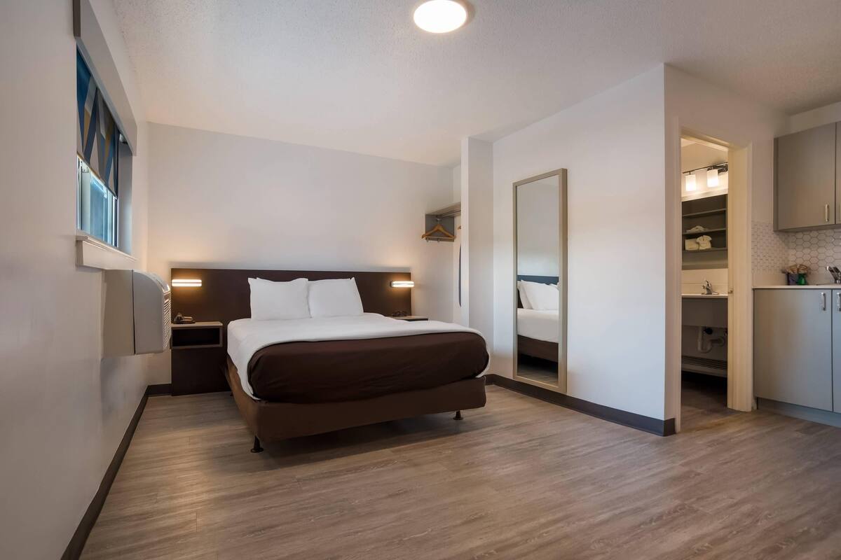 Een moderne hotelkamer met een groot bed, nachtkastjes, een spiegel en een inloopkast.