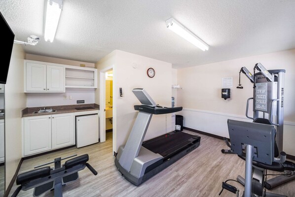Habitación de hotel con kitchenette, cinta de correr y máquina de pesas.