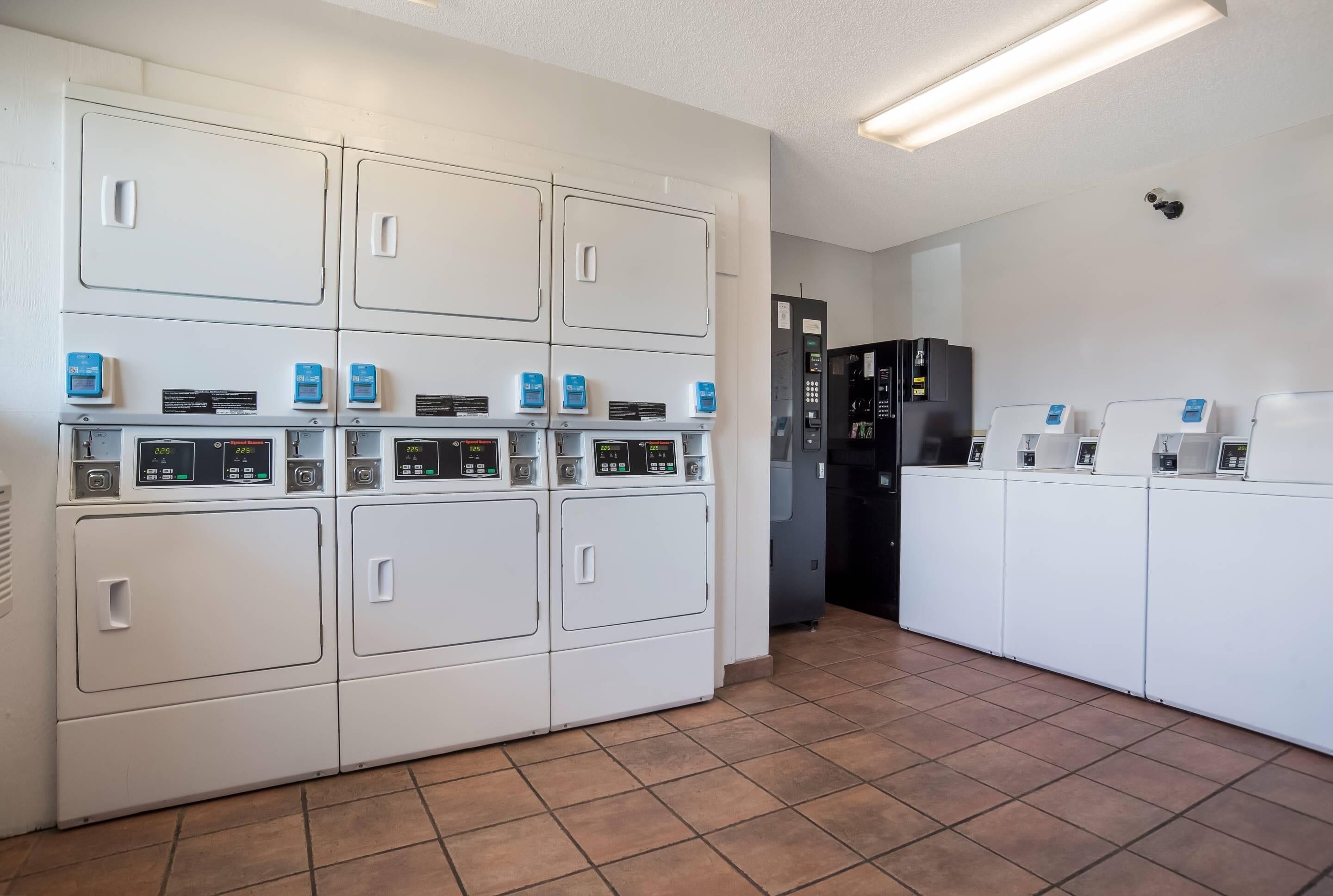 Eine Wäscherei mit mehreren Waschmaschinen und Trocknern, einer Kaffeemaschine und einem Kühlschrank.