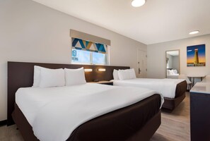 Habitación de hotel con dos camas, una ventana con vistas, un escritorio y una silla.