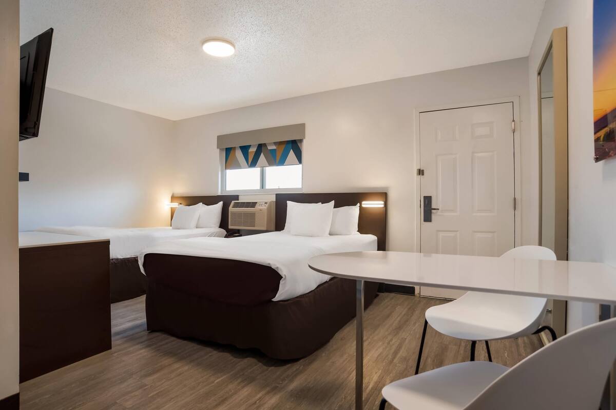 Een hotelkamer met twee bedden, een bureau en een stoel.