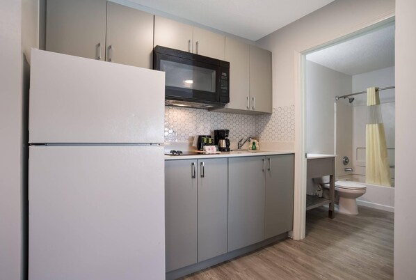 A compact kitchen with a refrigerator, microwave, and coffee maker.