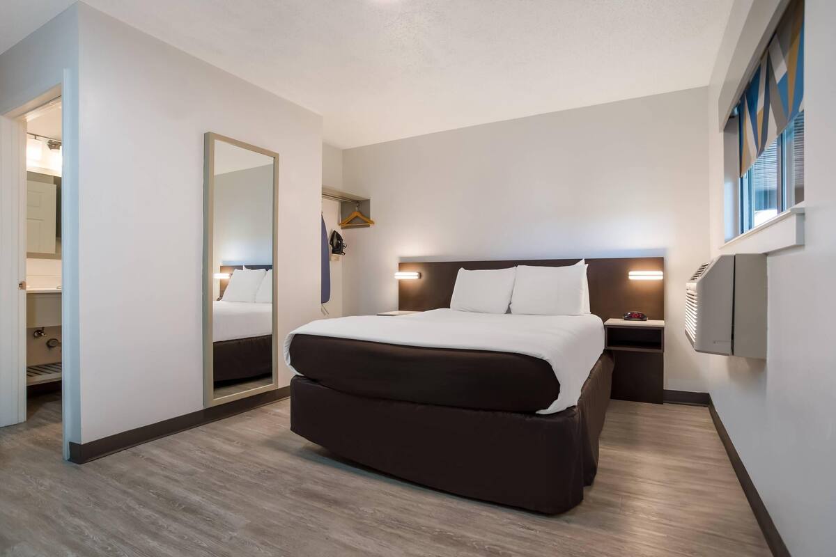 Een hotelkamer met een groot bed, een nachtkastje, een spiegel en een wandradiator.