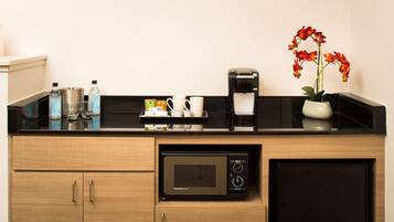 A kitchenette with a microwave, coffee maker, and various kitchen items on the counter.