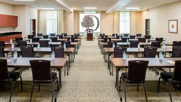 A conference room with rows of tables and chairs, a podium, and a projection screen displaying a tree.