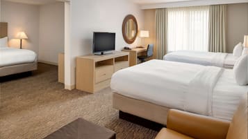 A hotel room with two beds, a desk with a television, a chair, a lamp, and a large mirror.