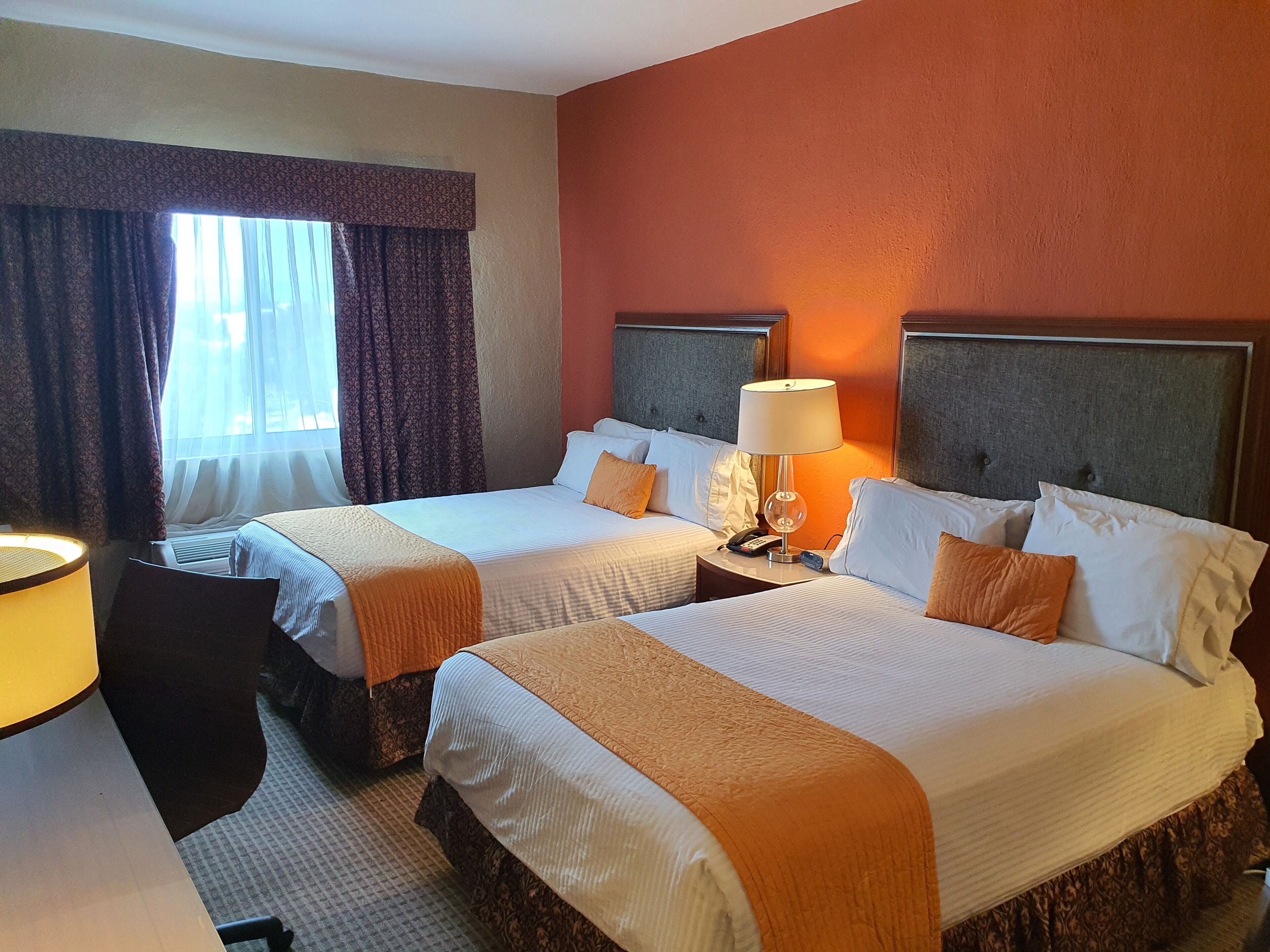 A hotel room with two beds, a desk, and a chair.