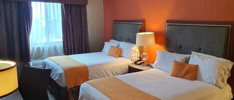 A hotel room with two beds, a desk, and a chair.