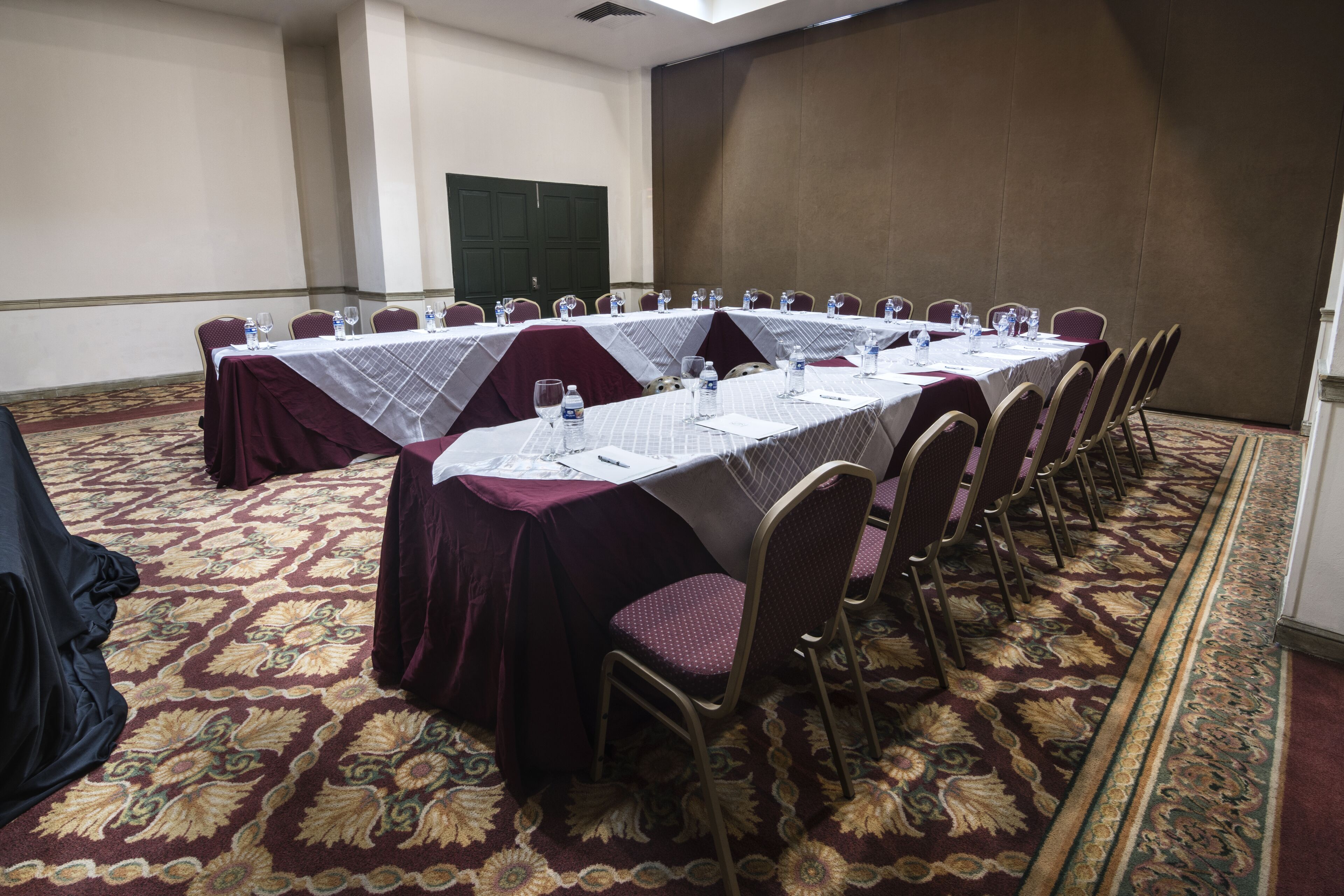 A conference room with a long table, chairs, and a carpeted floor.