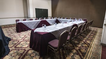 A conference room with a long table, chairs, and a carpeted floor.