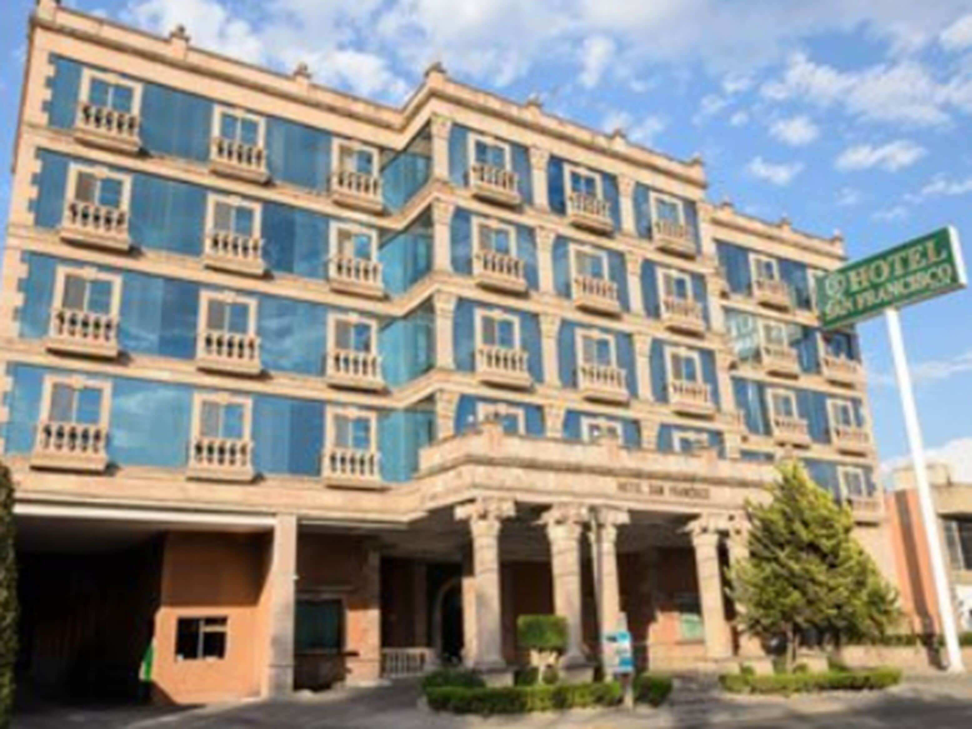 Un hôtel à plusieurs étages, doté d’une façade bleue, de nombreux balcons et d’une enseigne indiquant qu’il se trouve à San Francisco.