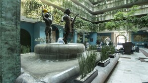 Un patio con una fuente central, estatuas y macetas.