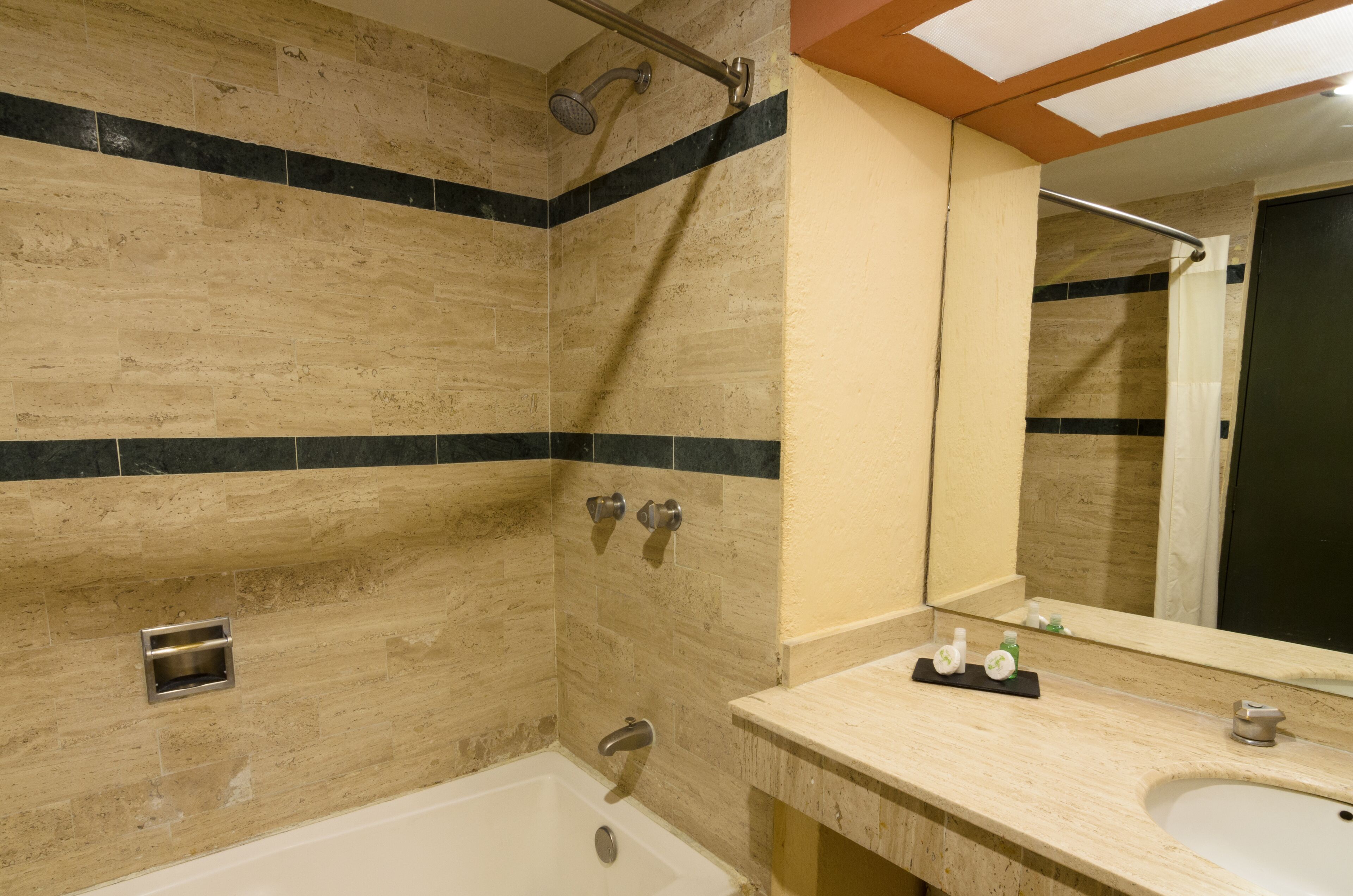 A bathroom with a bathtub, a shower, a sink, and a mirror.