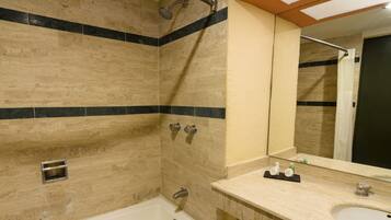 A bathroom with a bathtub, a shower, a sink, and a mirror.