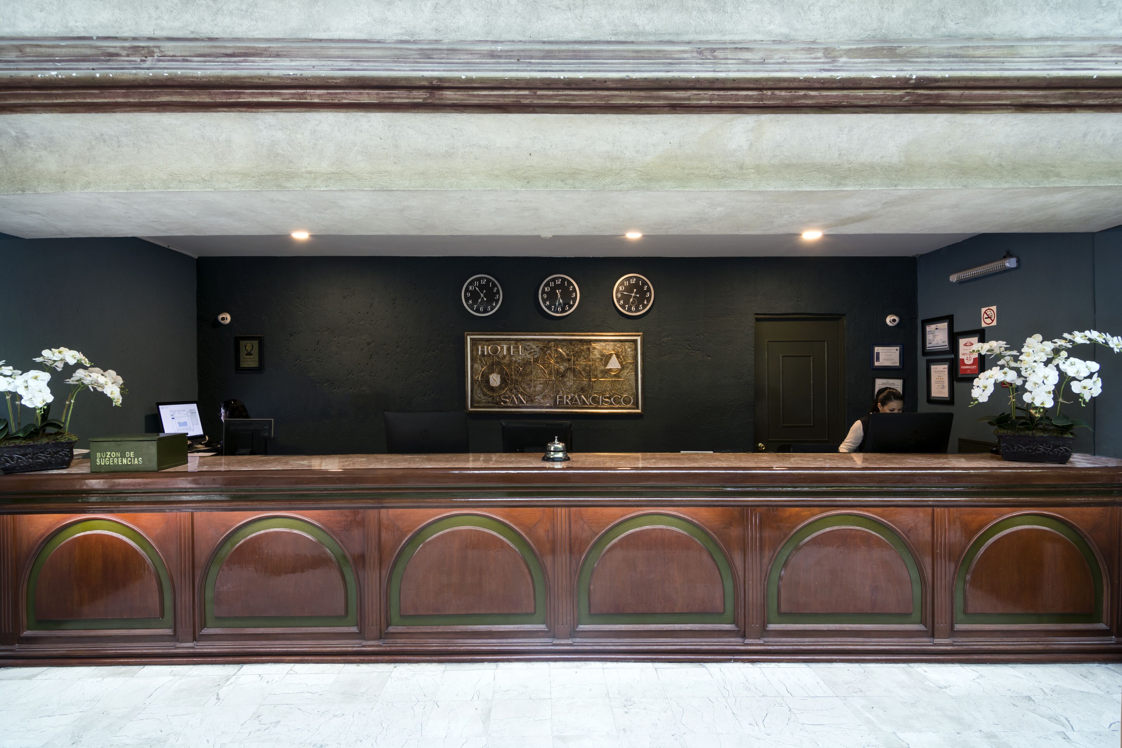 Una recepción con una pared oscura, tres relojes y un mapa enmarcado de San Francisco.