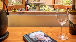 Un libro titulado "Livet med skatte og bøjer", una copa de vino y una botella sobre una mesa de madera.