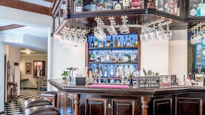 Zona de bar con suelo a cuadros, mostrador de madera y taburetes.
