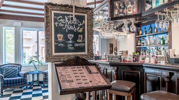 A bar area with a chalkboard menu, bar stools, and a variety of liquor bottles.
