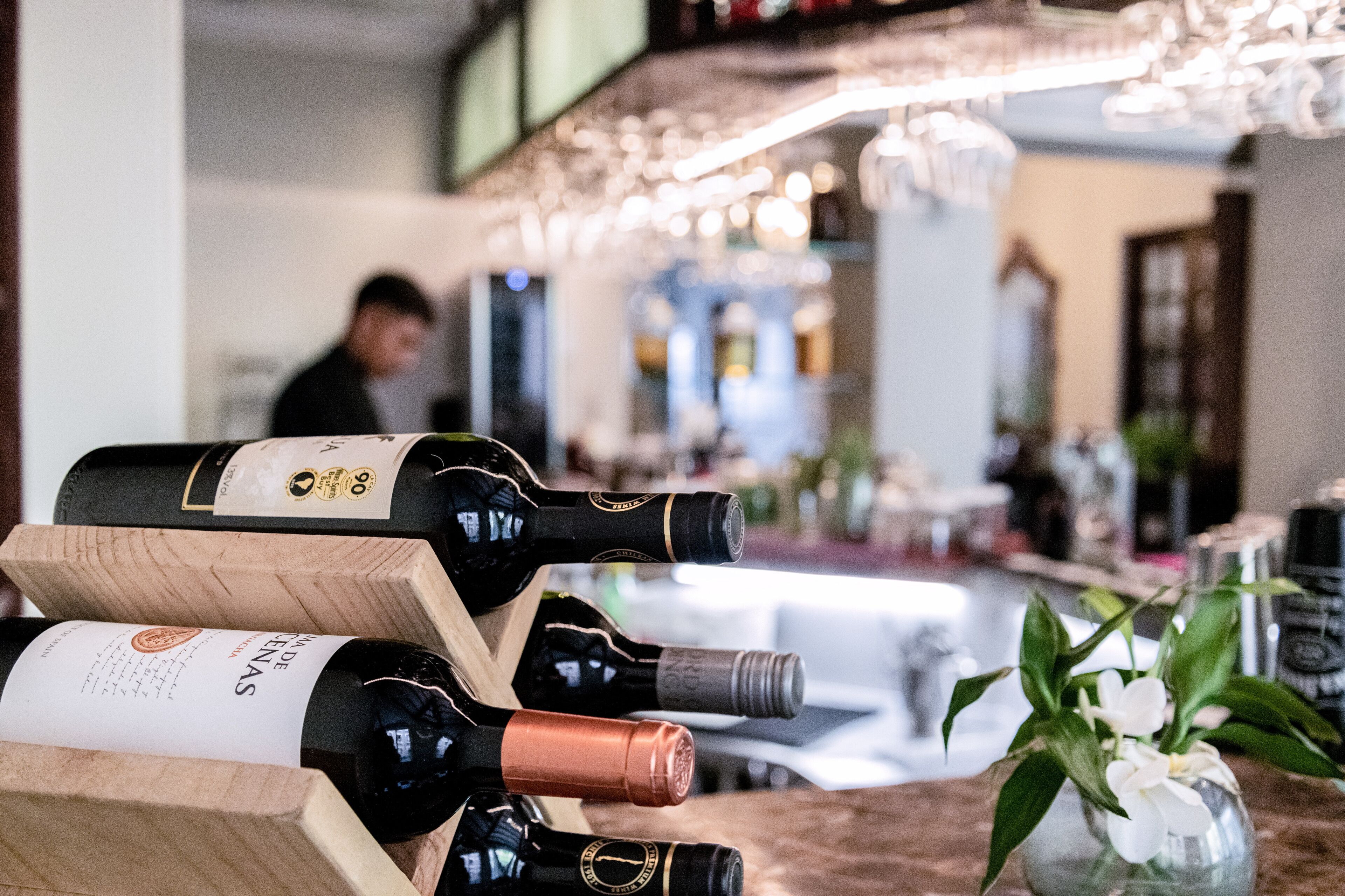 A bar area with multiple wine bottles displayed on wooden stands.