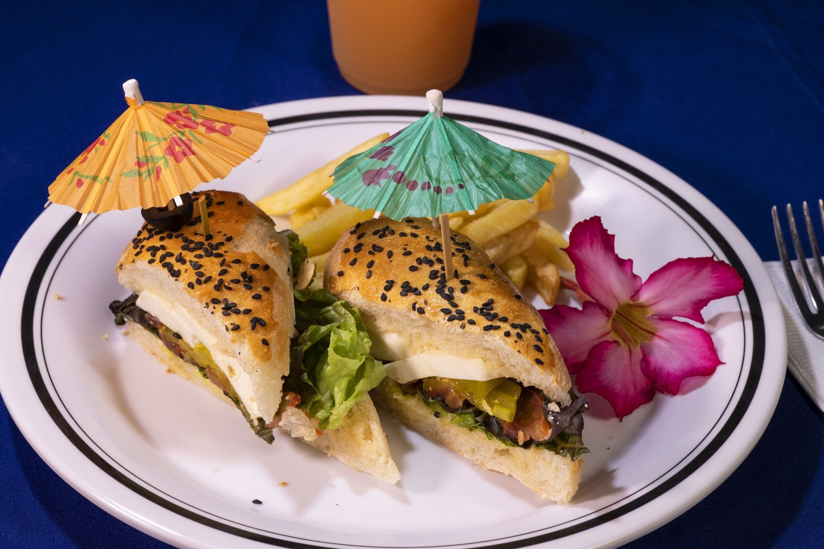 A plate with a sandwich, fries, and a flower.