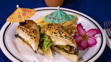 A plate with a sandwich, fries, and a flower.