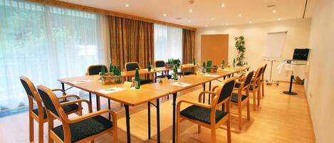A conference room with a long table, chairs, a projector, and a whiteboard.