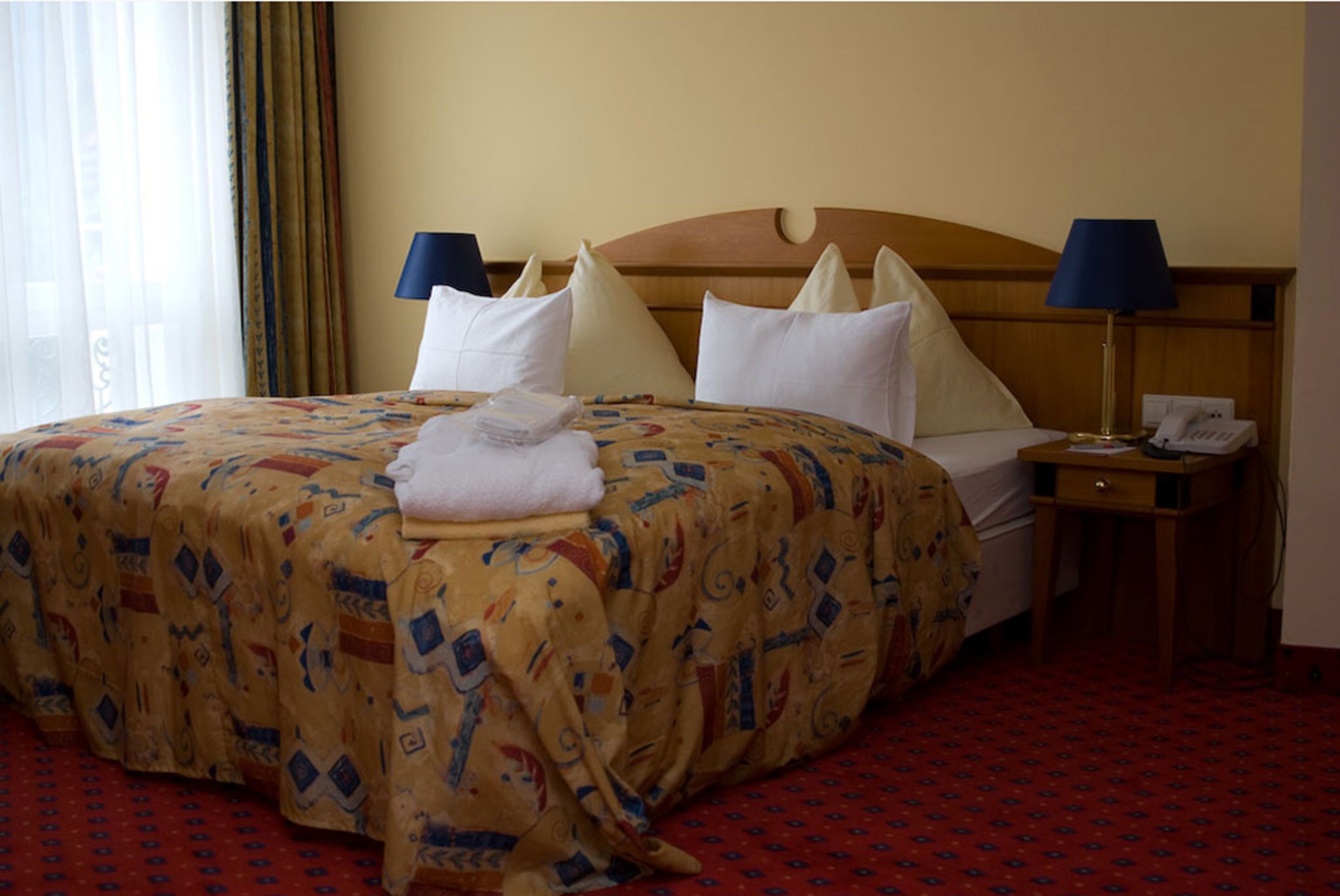 A hotel room with a large bed, two bedside tables, a lamp, and a telephone.