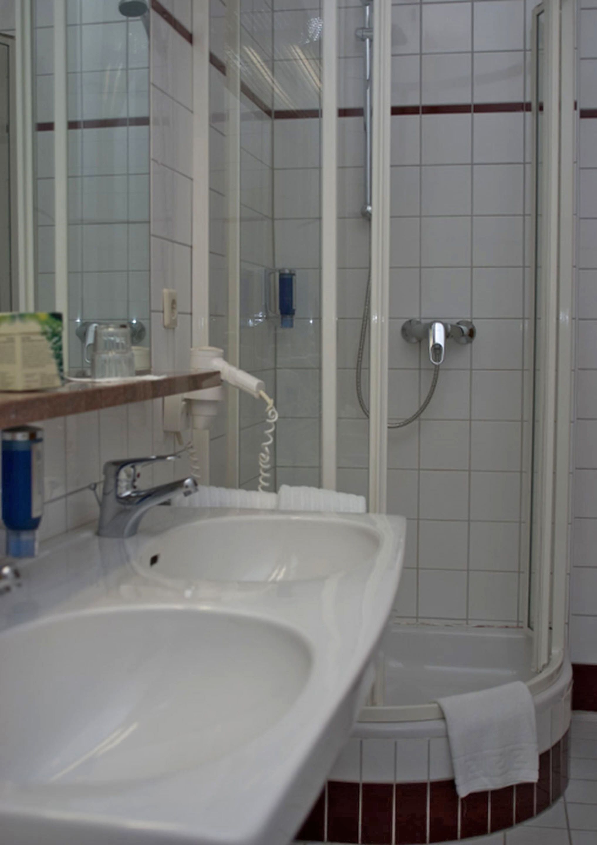 Ein Badezimmer mit weißem Waschbecken, Spiegel und Duschkabine.