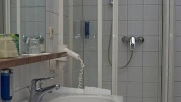 Ein Badezimmer mit weißem Waschbecken, Spiegel und Duschkabine.