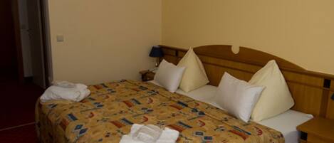 Una habitación de hotel con una cama, una mesita de noche y una lámpara.