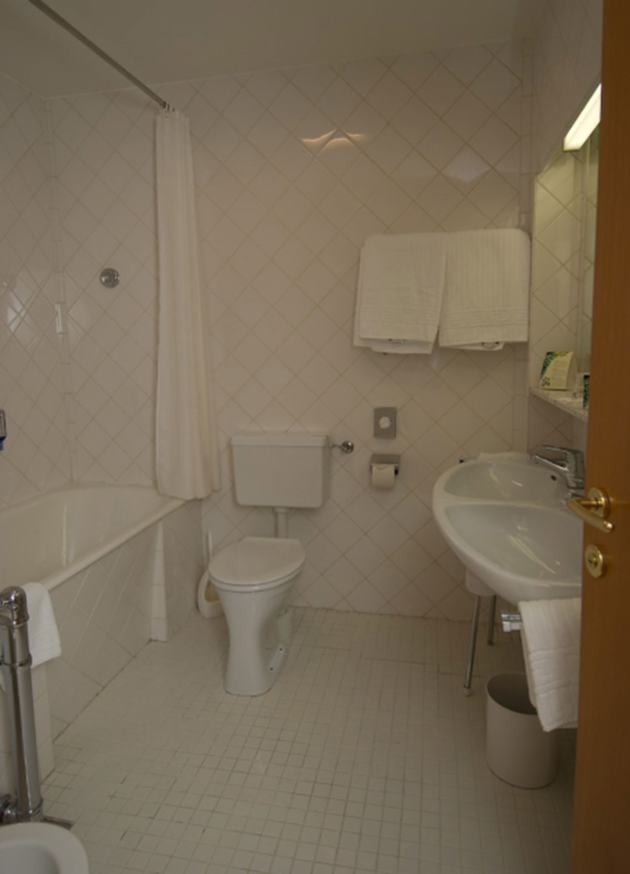 Un baño con bañera, inodoro, lavamanos y espejo.