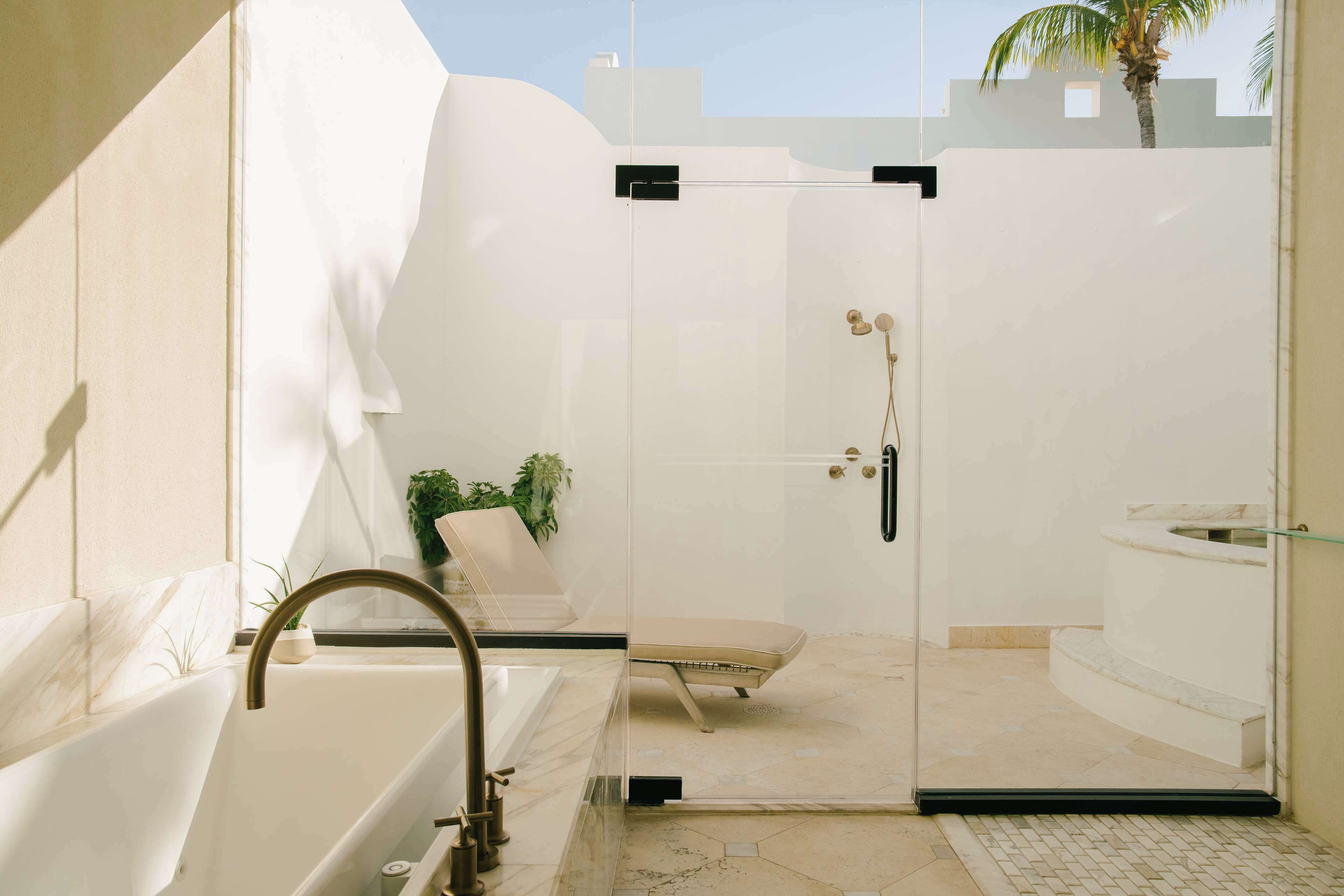 Un baño moderno con ducha envuelta en vidrio, una bañera y una zona de estar.