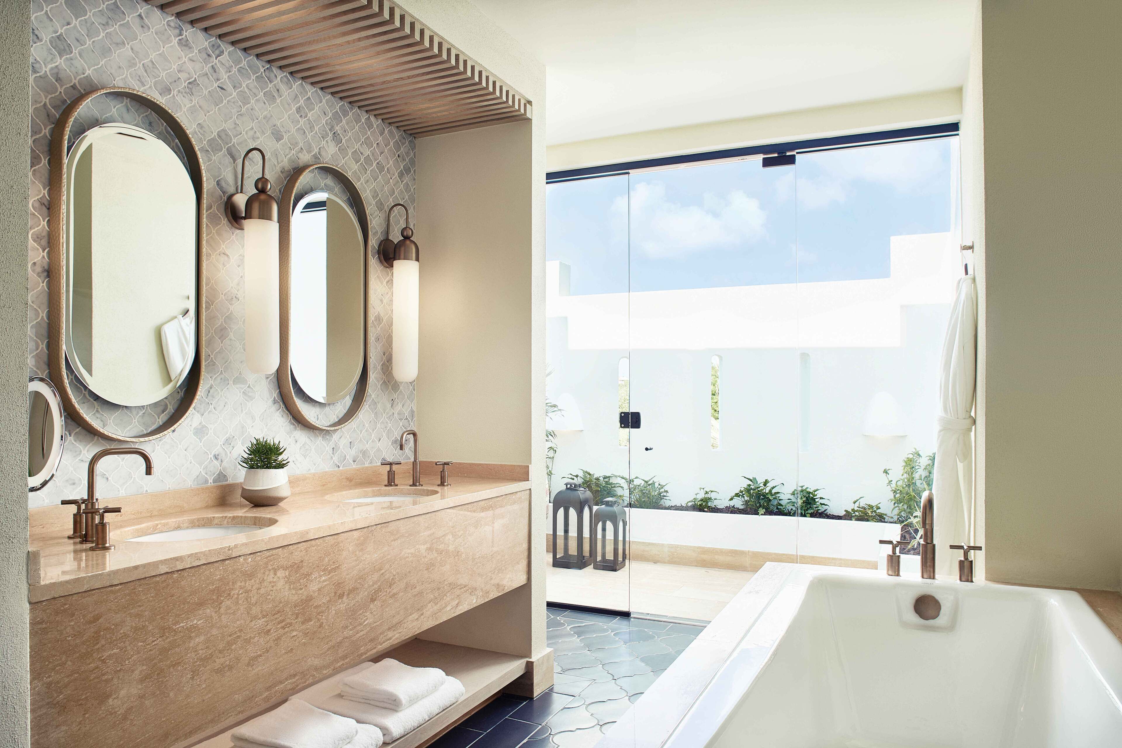 Ein modernes Badezimmer mit zwei Waschbecken, großen Spiegeln und einer Badewanne.