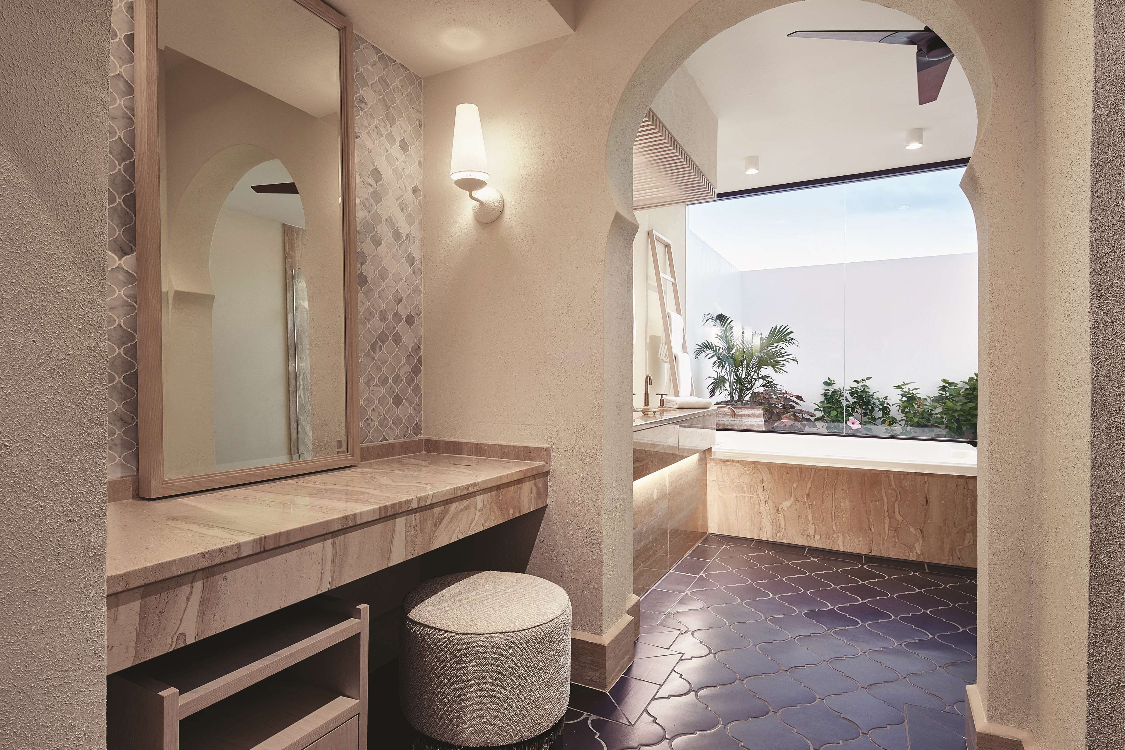 Uma casa de banho moderna com um espelho grande, toucador de madeira e vista para o exterior.