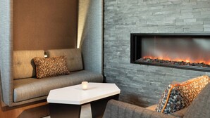 A modern living room with a stone wall, a sofa, a coffee table, and a fireplace. - Marriott Anchorage Downtown (Anchorage)