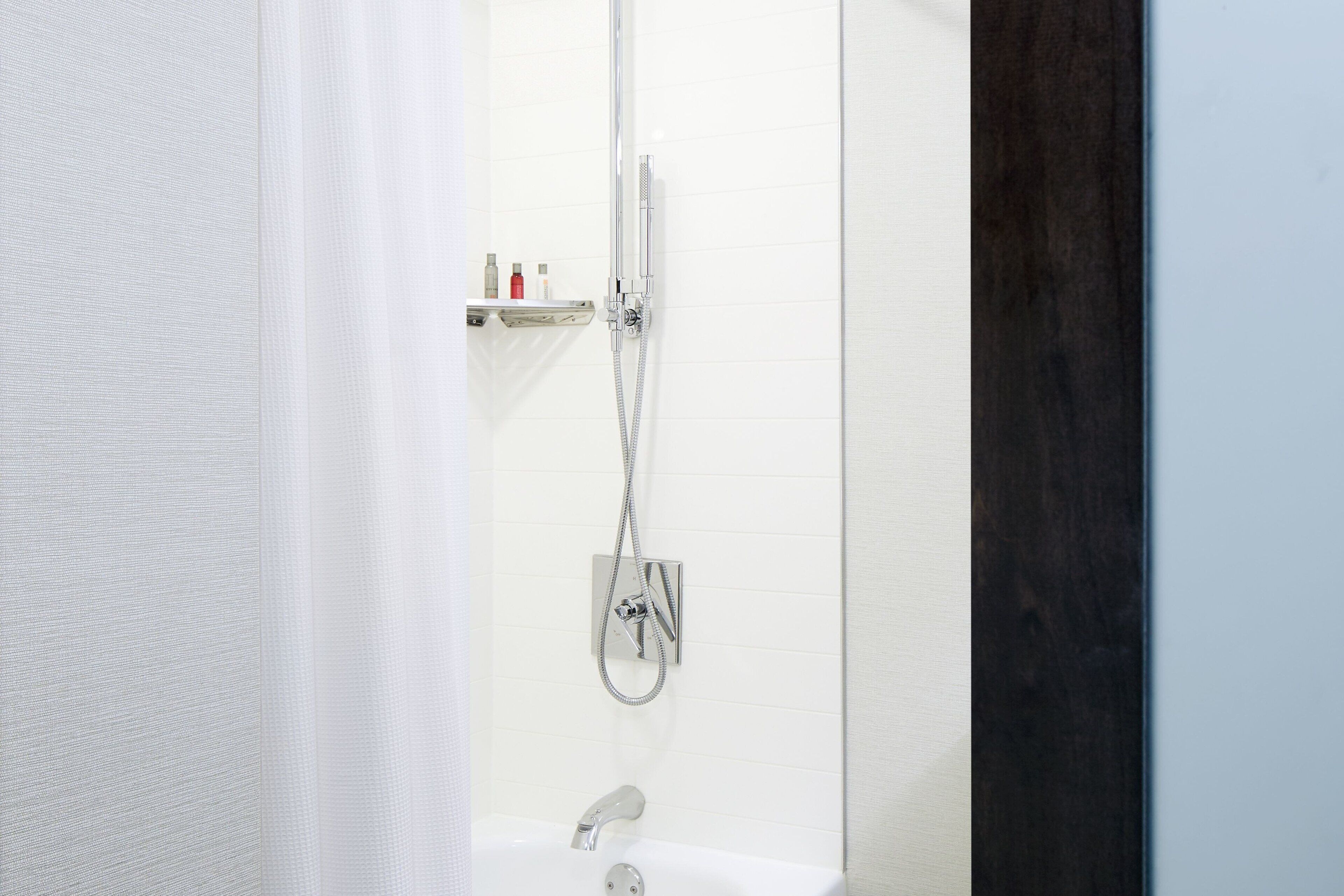 A bathroom with a shower, a sink, and a shelf with toiletries.