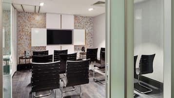 A modern waiting area with a flat-screen TV, black chairs, and a patterned wall.