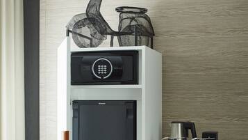 A modern kitchenette with a built-in refrigerator, a coffee maker, and a small table with cups and a kettle.