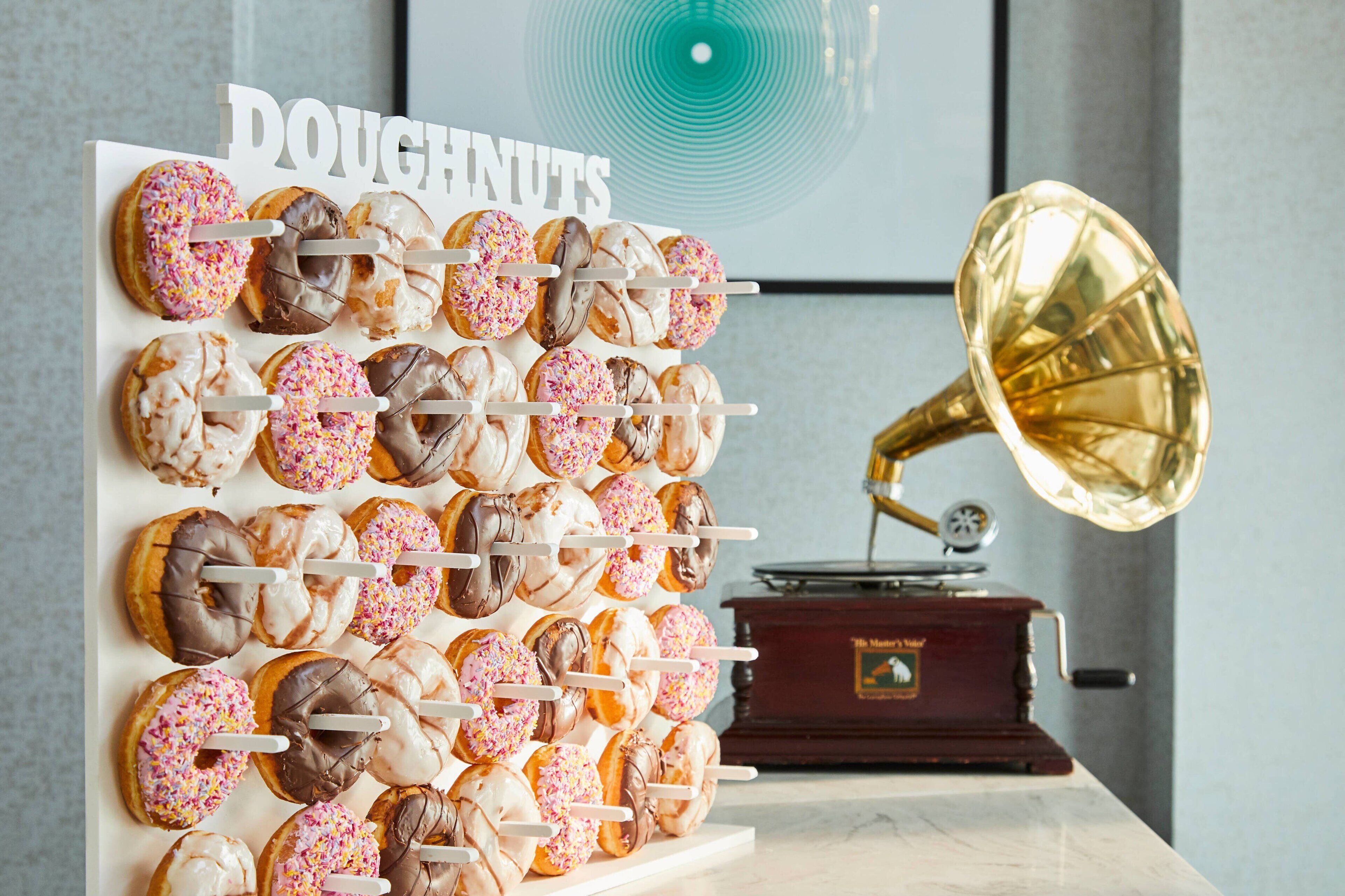 A wall display of assorted doughnuts with a gramophone in the background.