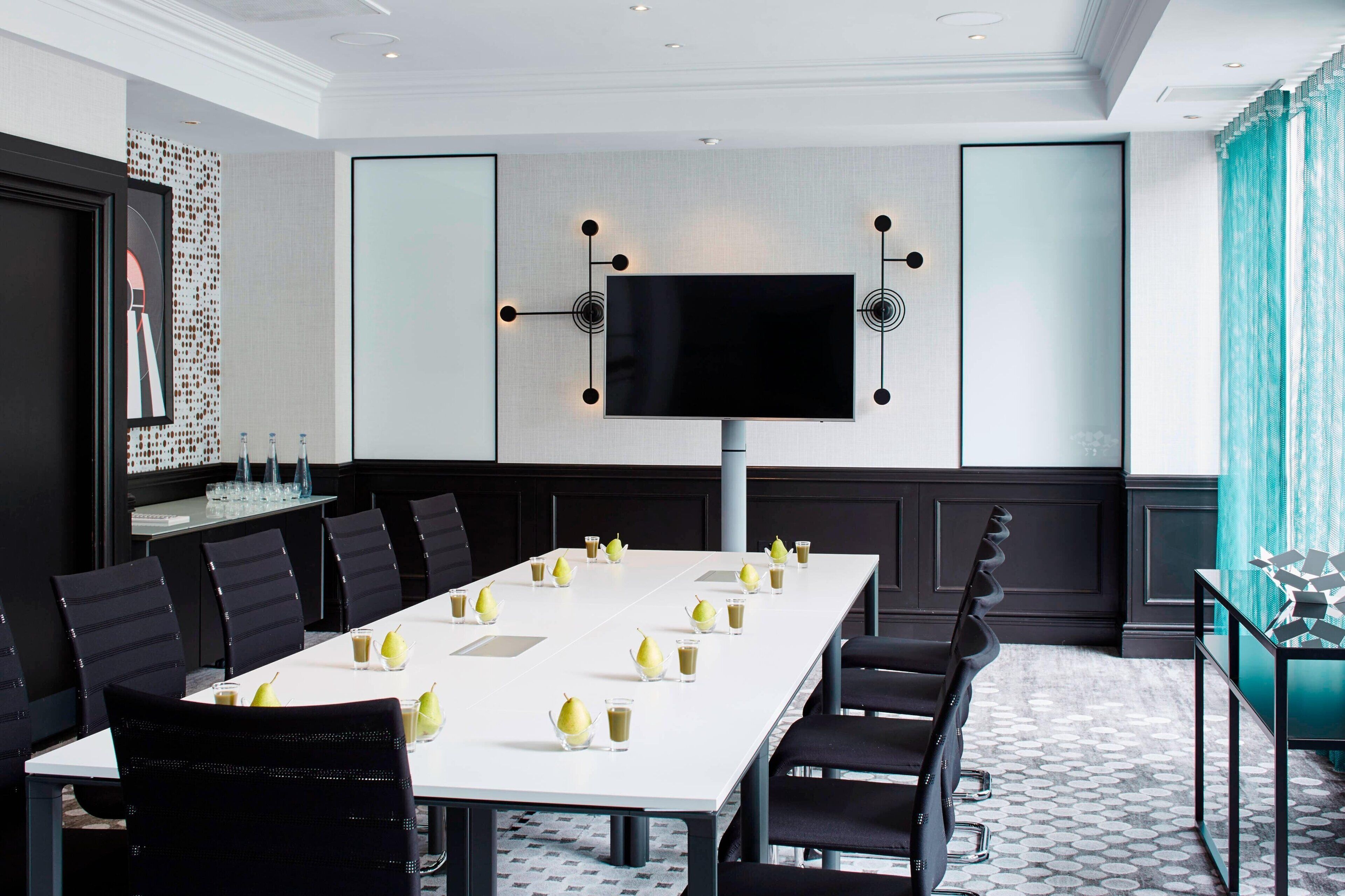 A conference room with a long table, chairs, a flat-screen TV, and a decorative wall panel.