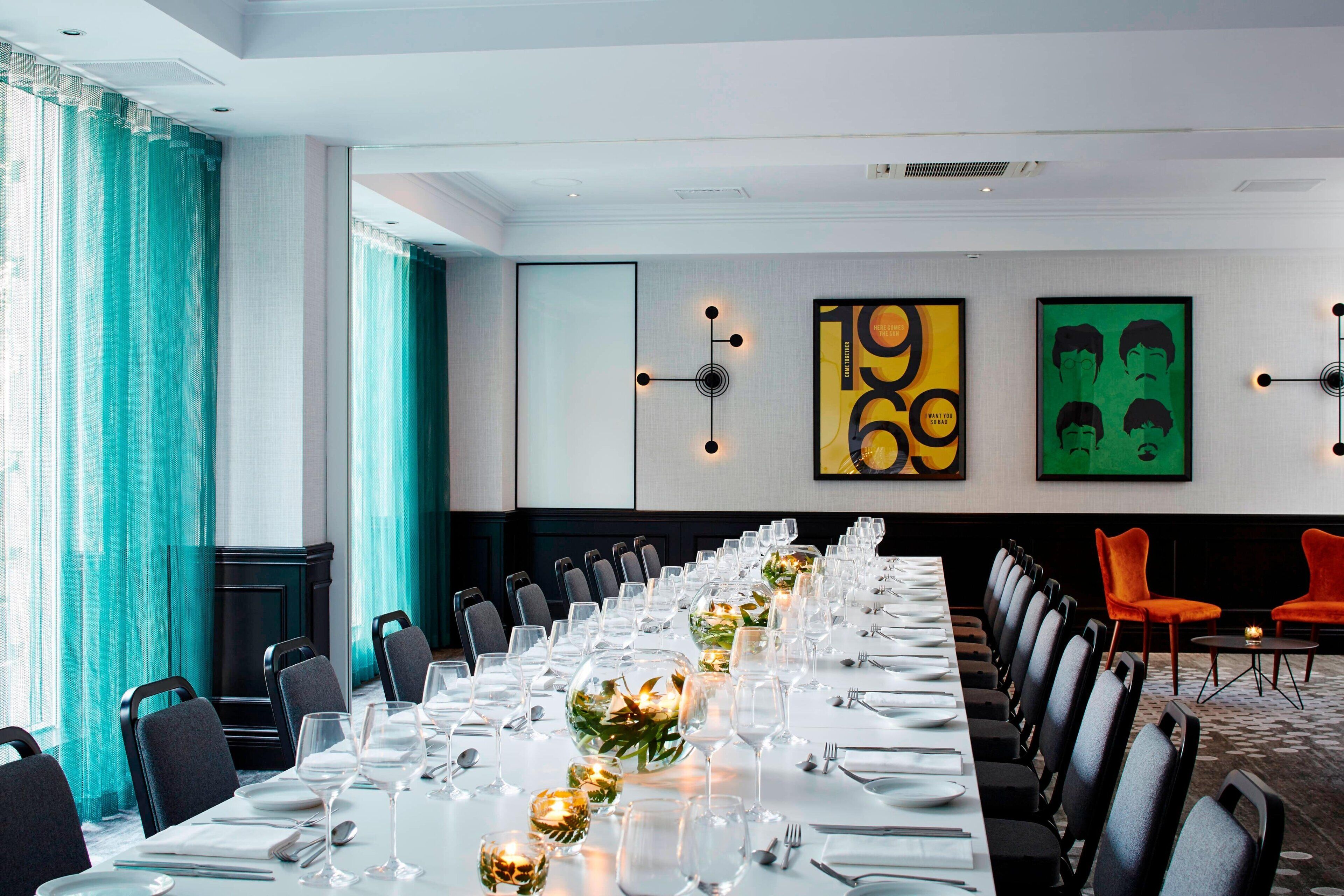 A conference room with a long table set for a meeting, chairs arranged around it, and artwork on the walls.