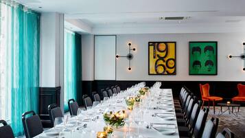 A conference room with a long table set for a meeting, chairs arranged around it, and artwork on the walls.