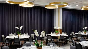 A conference room with round tables, black chairs, and white table settings.