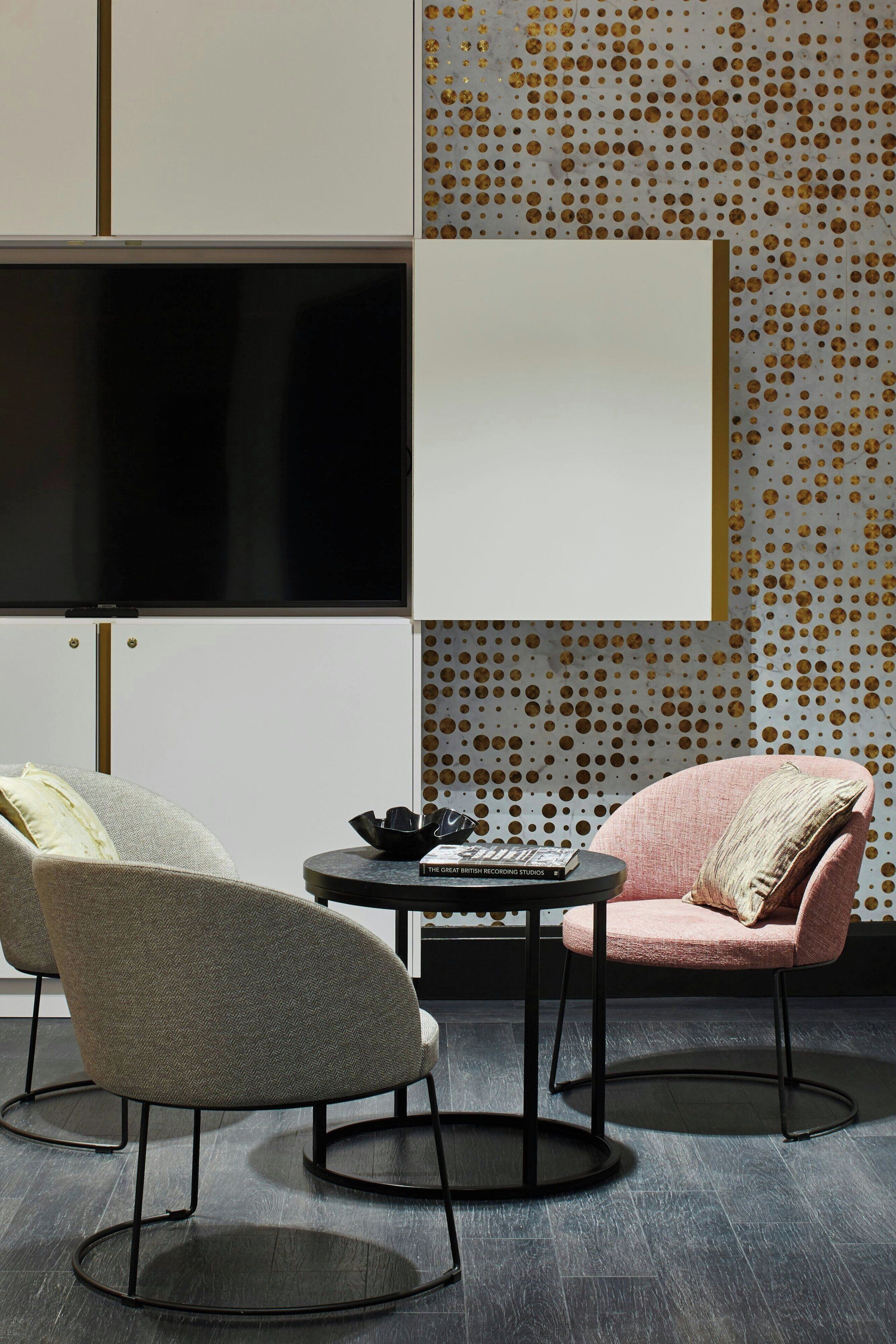 A modern room with two chairs, a table, and a large screen.