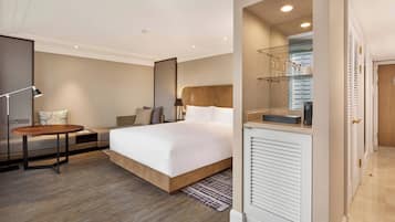 Una habitación de hotel moderna con una cama grande, una mesita de noche, un escritorio y un espejo.