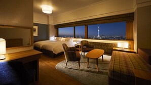 A hotel room with a bed, two chairs, a desk, and a view of a cityscape at night. - Tobu Hotel Levant Tokyo (Tokyo)