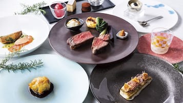 A variety of plated dishes including steak, vegetables, and desserts on a dining table.